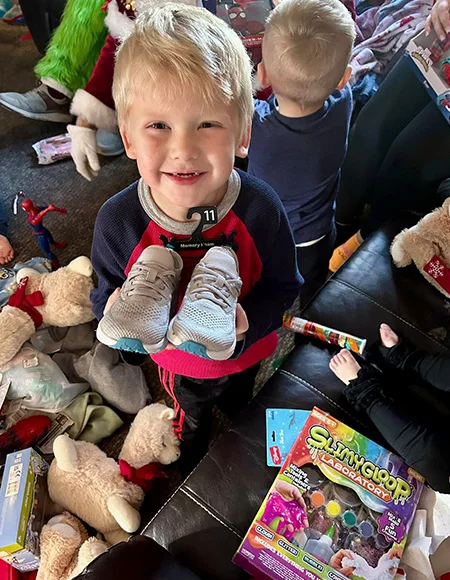 A child receiving new shoes and gifts through the Adopt-A-Family program